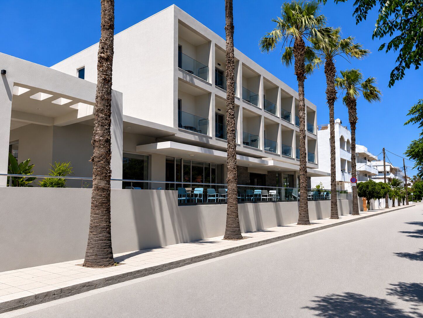 Un hôtel moderne doté de nombreux balcons, de palmiers et offrant une vue sur un ciel bleu azur.
