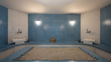 Bathroom features a large hot tub, two wall-mounted sinks, and blue mosaic tiles.