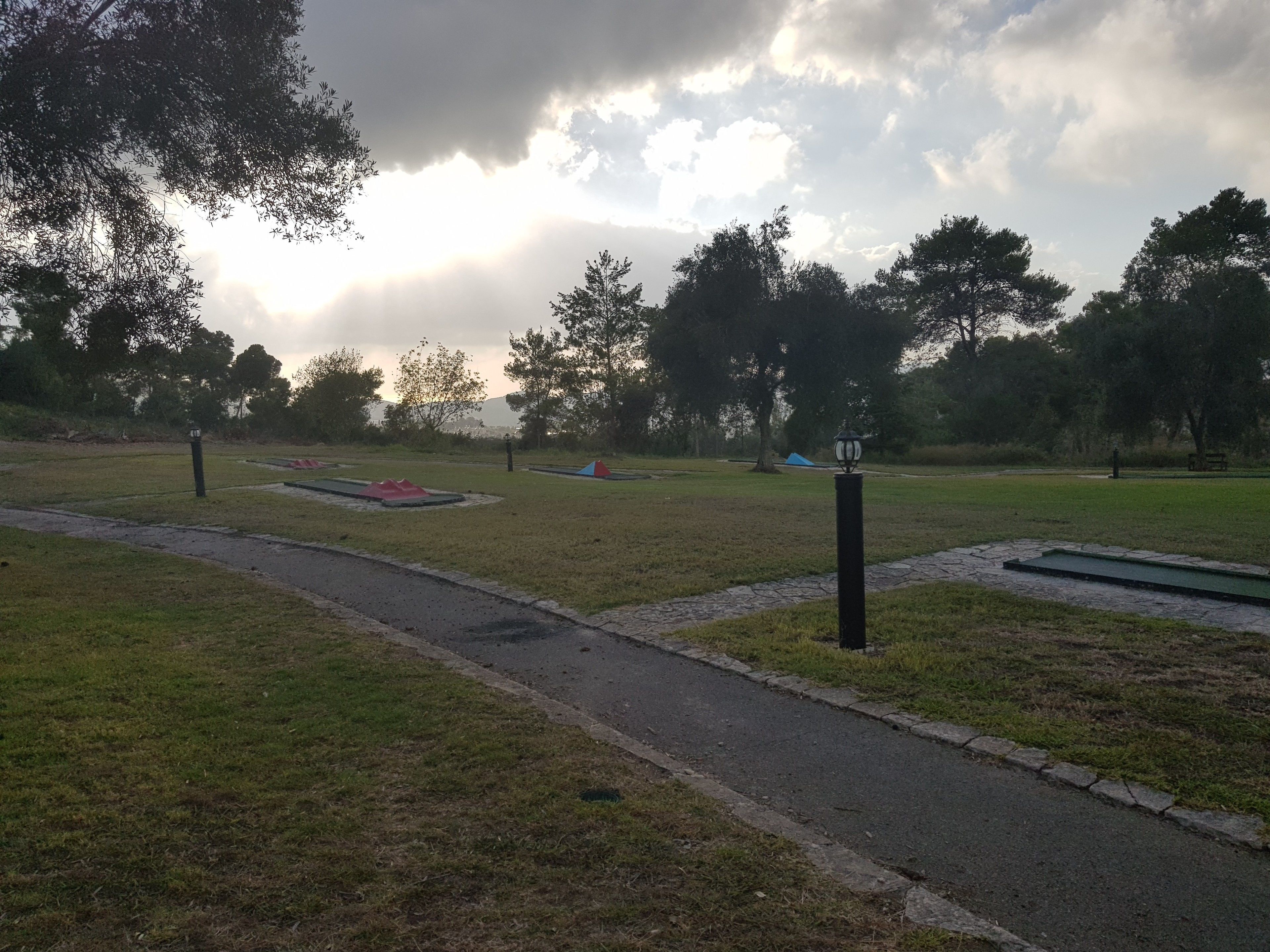 A park with a paved path, grassy areas, and trees.