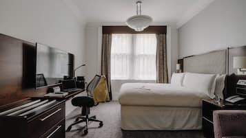Ein Hotelzimmer mit einem großen Bett, einem Schreibtisch, einem Flachbildfernseher, einem Stuhl und einem Kleiderschrank.