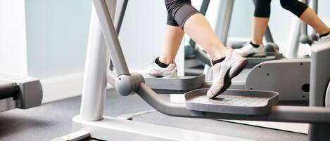 A treadmill in a gym with a grey floor and a light blue wall.