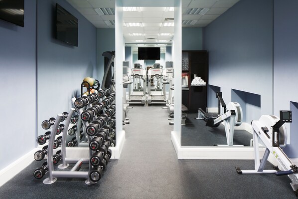 A gym with exercise equipment, including dumbbells, treadmills, and a stationary bike.