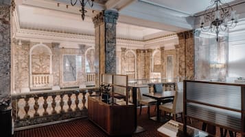 Eine luxuriöse Lobby mit Marmorsäulen, einem Empfangstresen und stilvollen Kronleuchtern.
