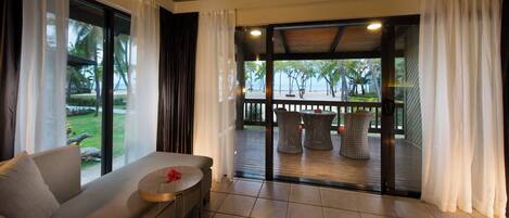 A modern room with a sofa, a small table, and a view of an outdoor deck with wicker furniture.