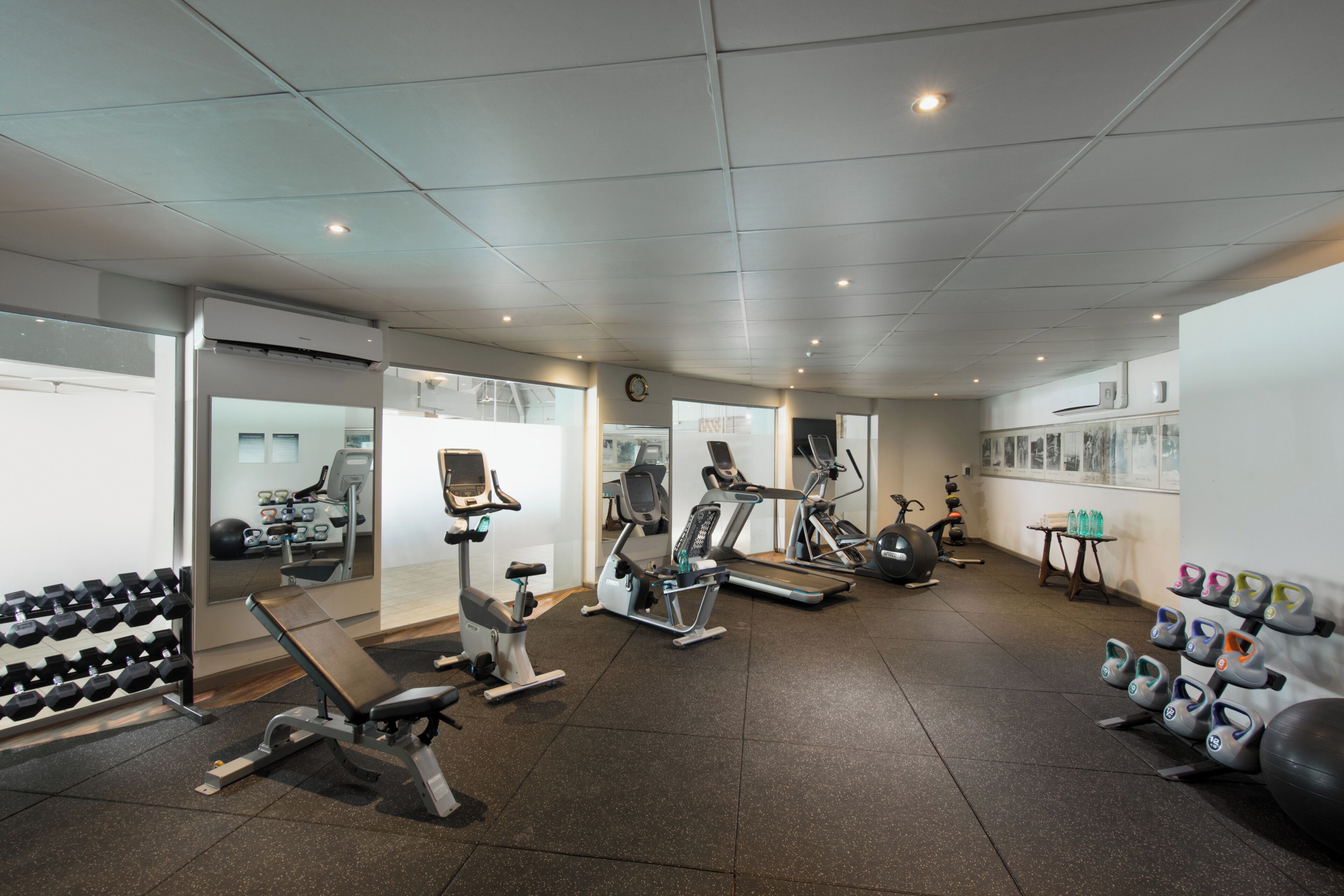 Een sportschool met trainingsapparatuur, een spiegel en een schoenenrek.