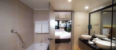 Un baño moderno con bañera, dos lavabos y un espejo grande.