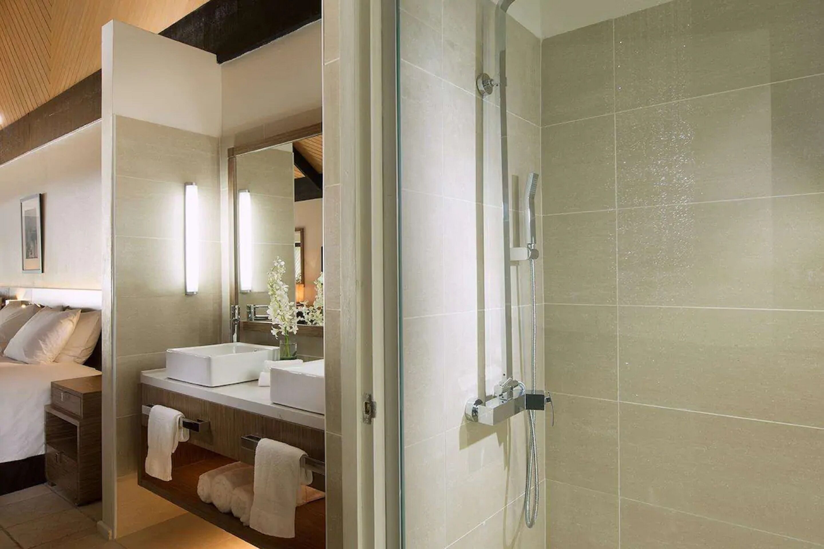 A modern bathroom with a glass-enclosed shower, a white sink, and a large mirror.