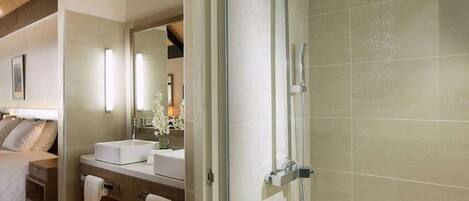 Ein modernes Badezimmer mit einer Glaskabine zur Dusche, einem weißen Waschbecken und einem großen Spiegel.