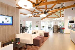 Un moderno vestíbulo de hotel con techo de madera, zona de estar y mostrador de recepción.