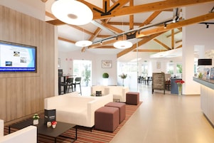 Un moderno vestíbulo de hotel con techo de madera, zona de estar y mostrador de recepción.