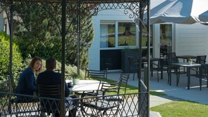 A gazebo with a metal roof and a decorative top, surrounded by a metal fence. There are tables and chairs inside the gazebo. - Best Western Hotel Wavre (Wavre)