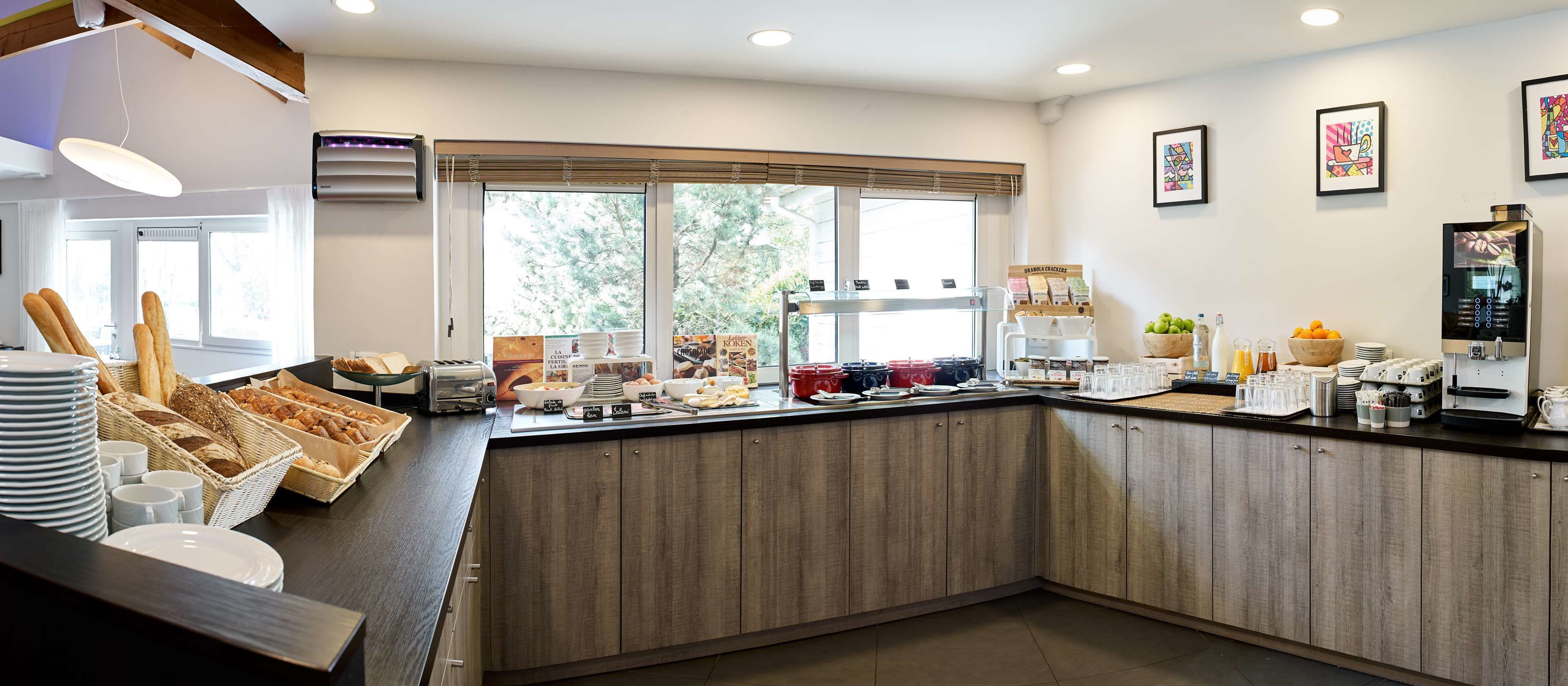 Un buffet pour le petit-déjeuner proposant du pain, des viennoiseries et des machines à café.