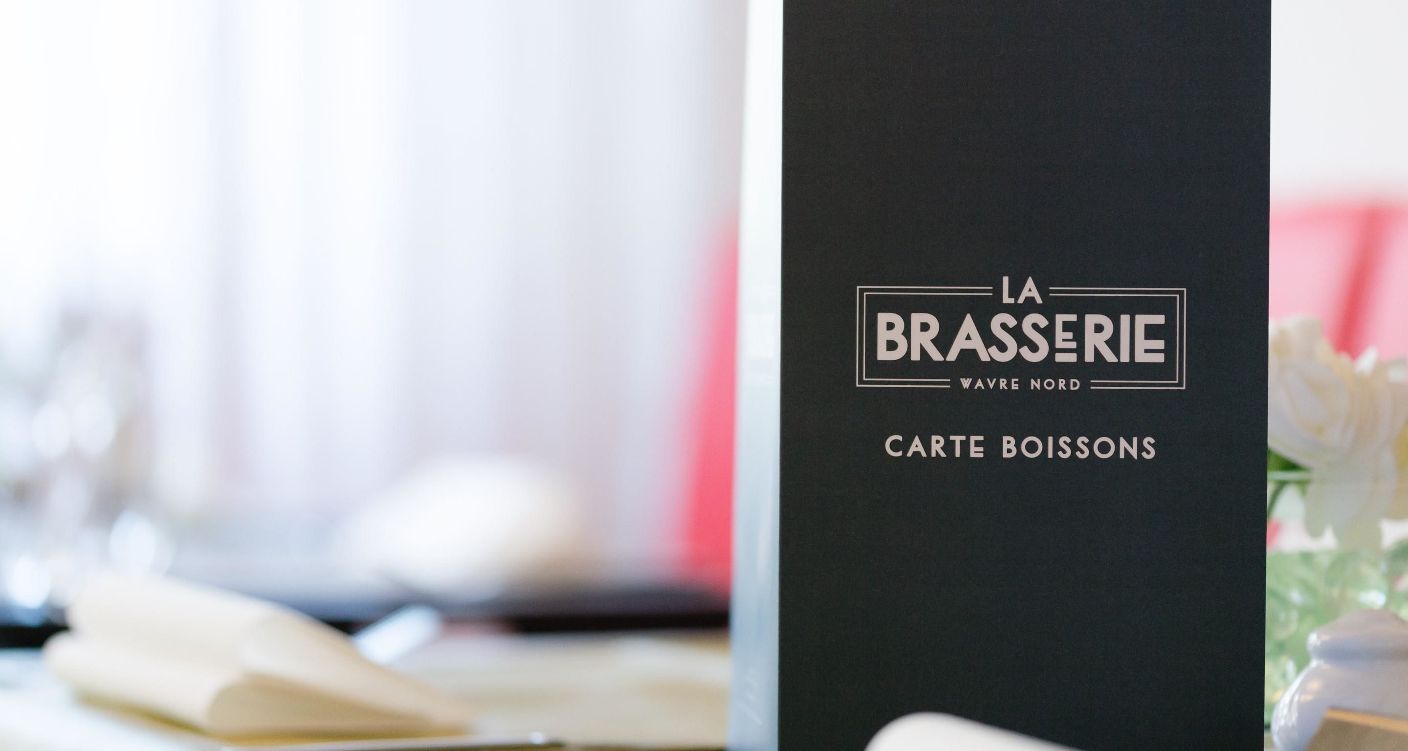 Un panneau de menu noir sur lequel on peut lire les inscriptions « LA BRASSERIE WAVRE NORD » et « CARTE DES BOISSONS ».
