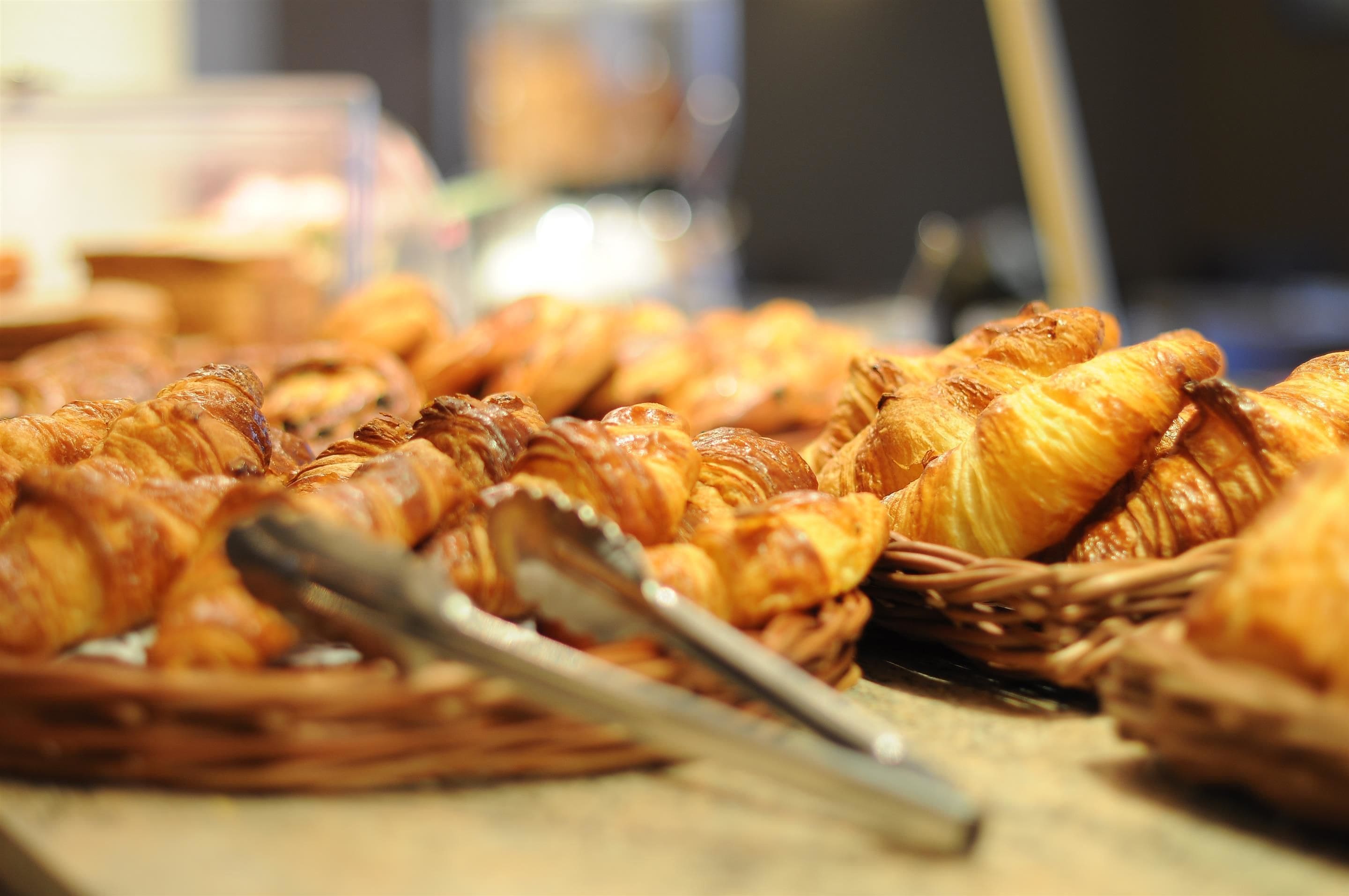A display of pastries, likely croissants, arranged on a table with tongs.