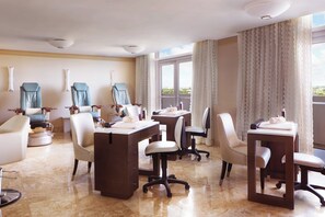 A hotel room with a balcony, multiple seating areas, and a desk.
