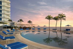 A pool area with lounge chairs, umbrellas, and palm trees. - The Ritz-Carlton, Fort Lauderdale (Fort Lauderdale)