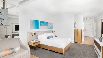 Una habitación de hotel moderna con una cama grande, un sofá, un escritorio y un televisor.
