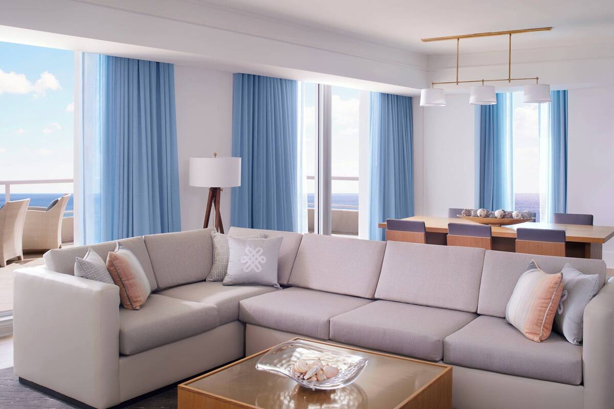 A modern living room with a sectional sofa, a coffee table, and a dining area with a table and chairs.