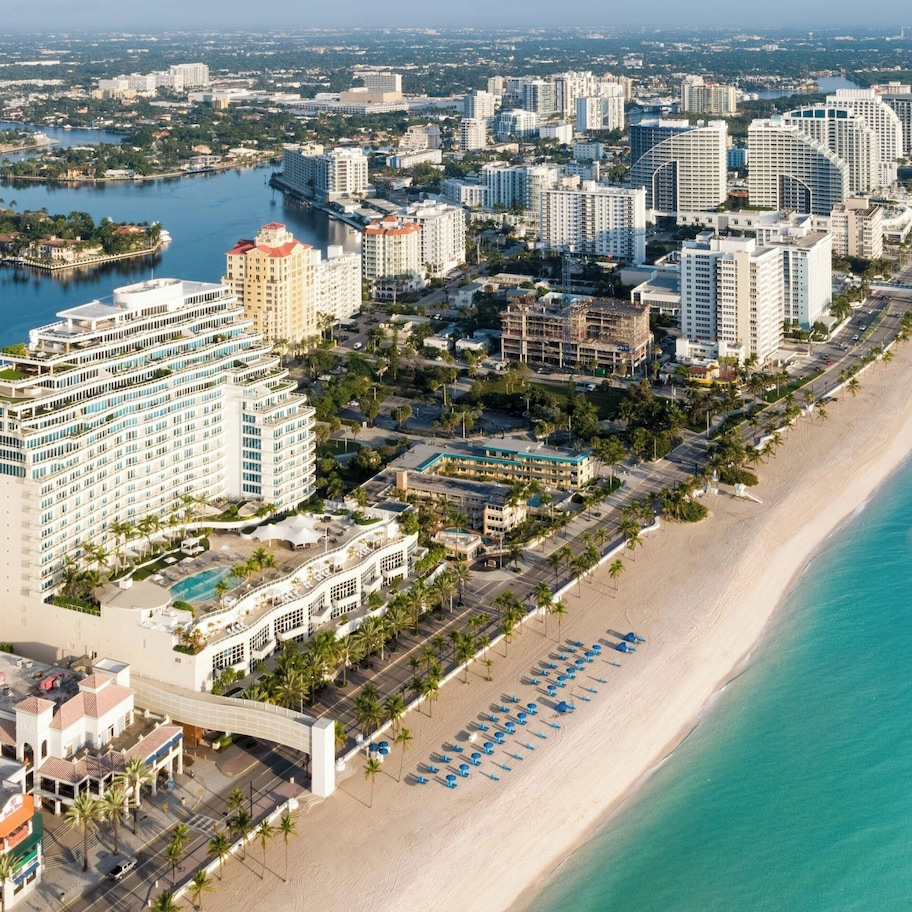 A coastal cityscape with high-rise hotels, a beach, and a marina.