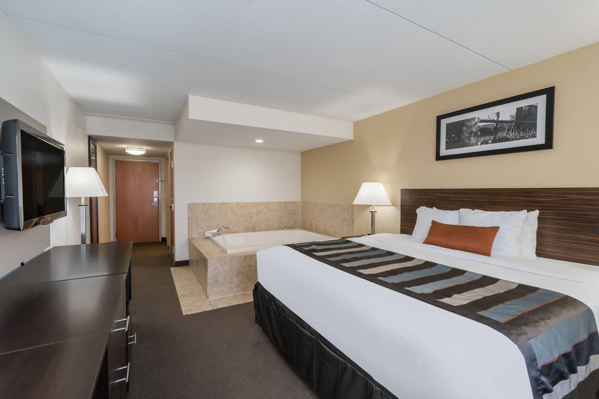 Ein Hotelzimmer mit Bett, Schreibtisch, Fernseher, Badezimmer und einem gerahmten Bild an der Wand.