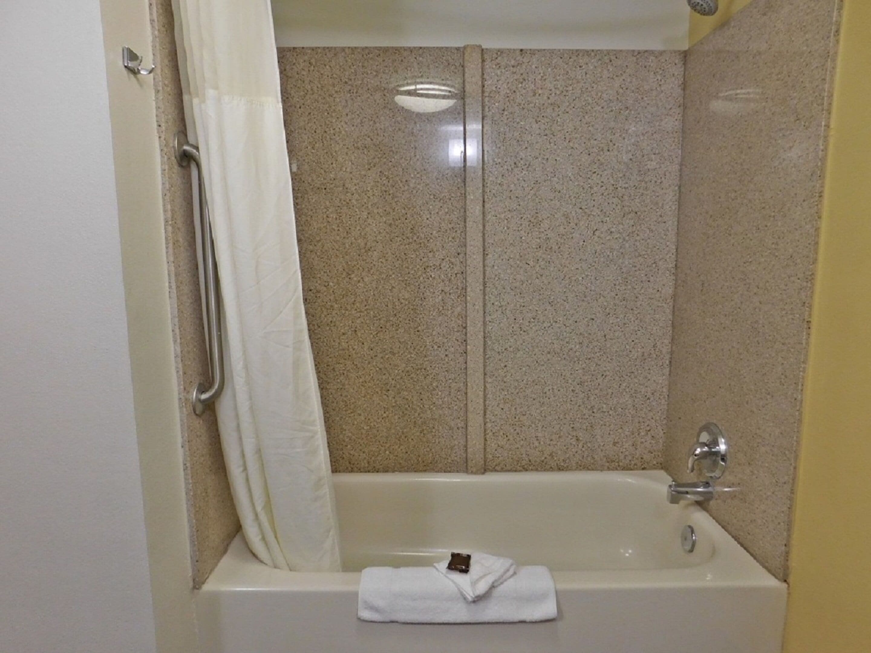 A bathroom with a bathtub, a shower curtain, and a towel.
