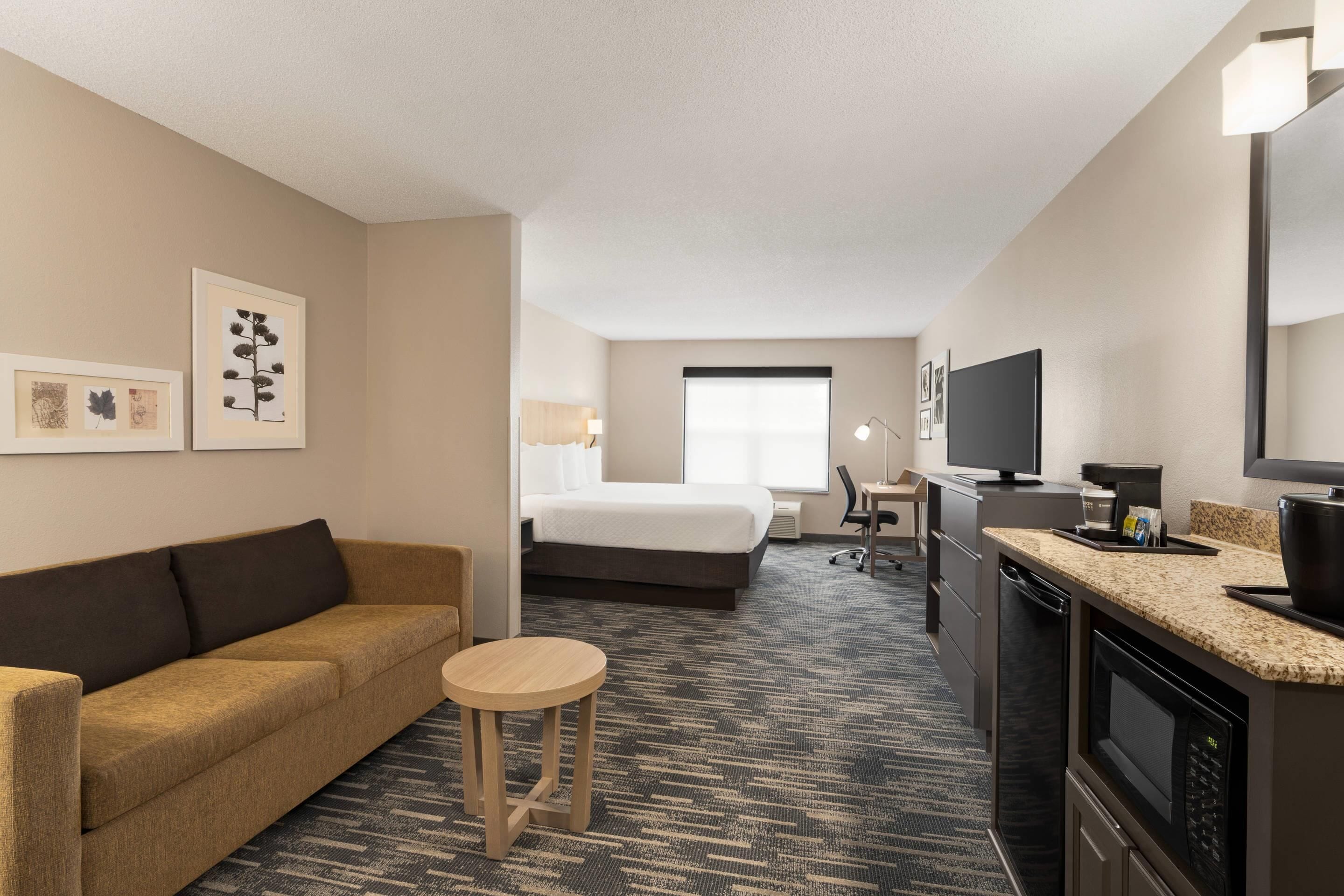 Een hotelkamer met een bed, een slaapbank, een klein rond tafeltje, een bureau, een televisie, een magnetron en een koffiezetapparaat.