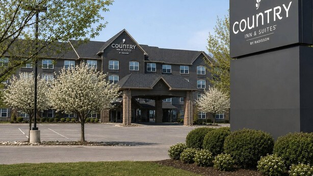 Un bâtiment Country Inn & Suites avec une façade en briques, de nombreuses fenêtres et une entrée abritée.