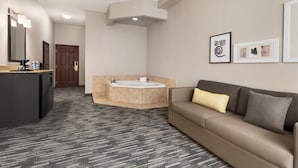 Une salle de bain d’hôtel avec une baignoire, un lavabo et un miroir. On y trouve un porte-serviettes et un tableau encadré accroché au mur.