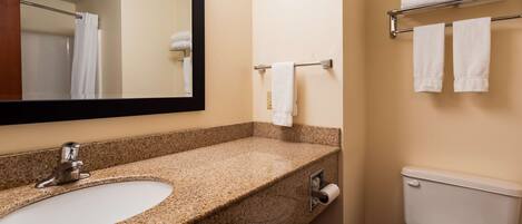 A bathroom with a granite countertop sink, a mirror, a towel rack, and a toilet.