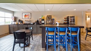 A modern kitchen with a central island, bar stools, and a dining table with chairs. - Best Western Nittany Inn Milroy (Reedsville)
