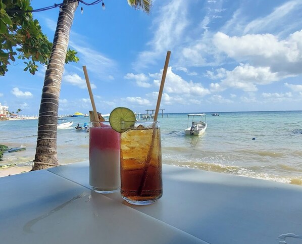 Two drinks on a table with a view of the sea and boats in the background. - Villas Sacbe Condo Hotel and Beach Club (Playa del Carmen)