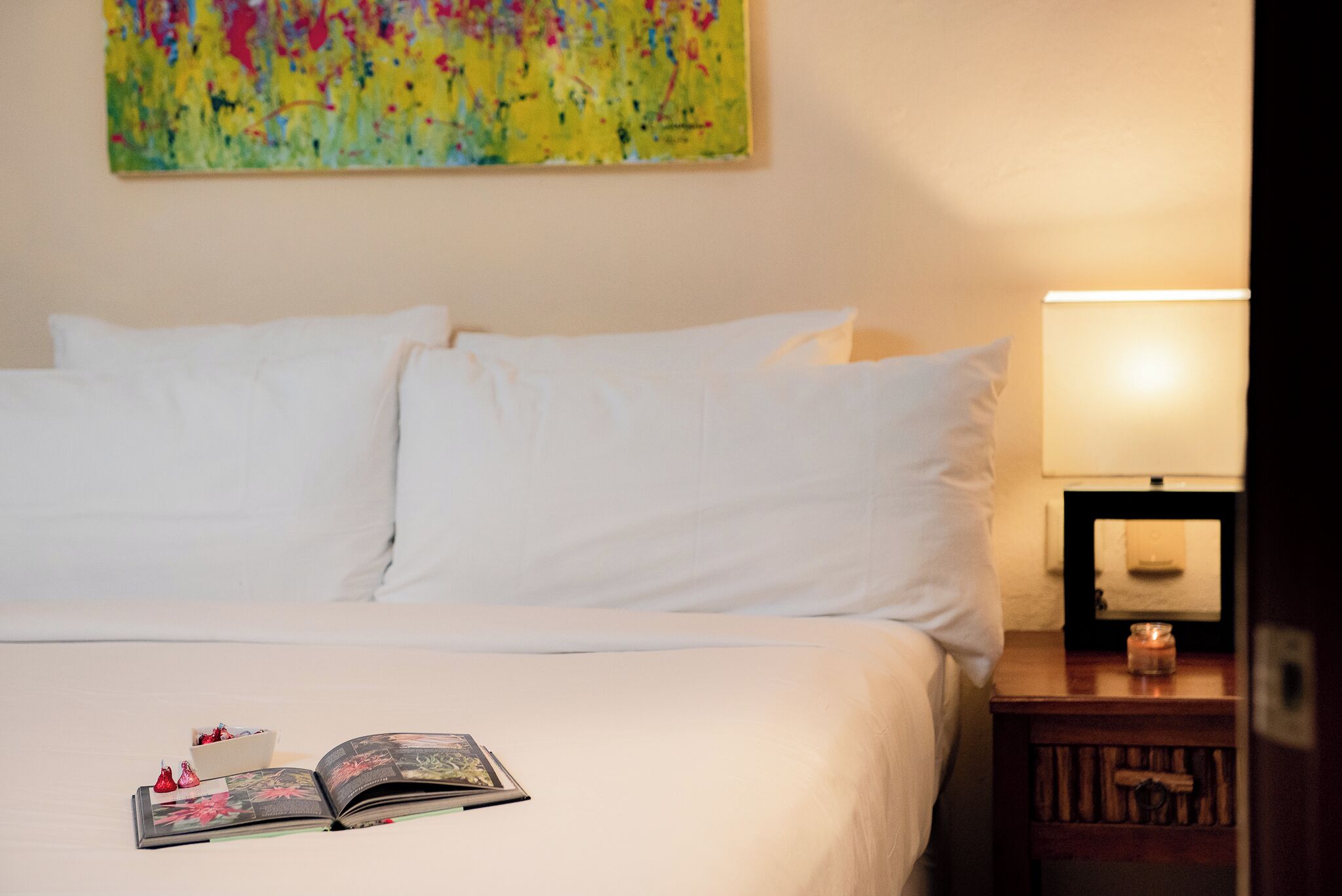 A neatly made bed with white linens, a book, and decorative items on the bed.
