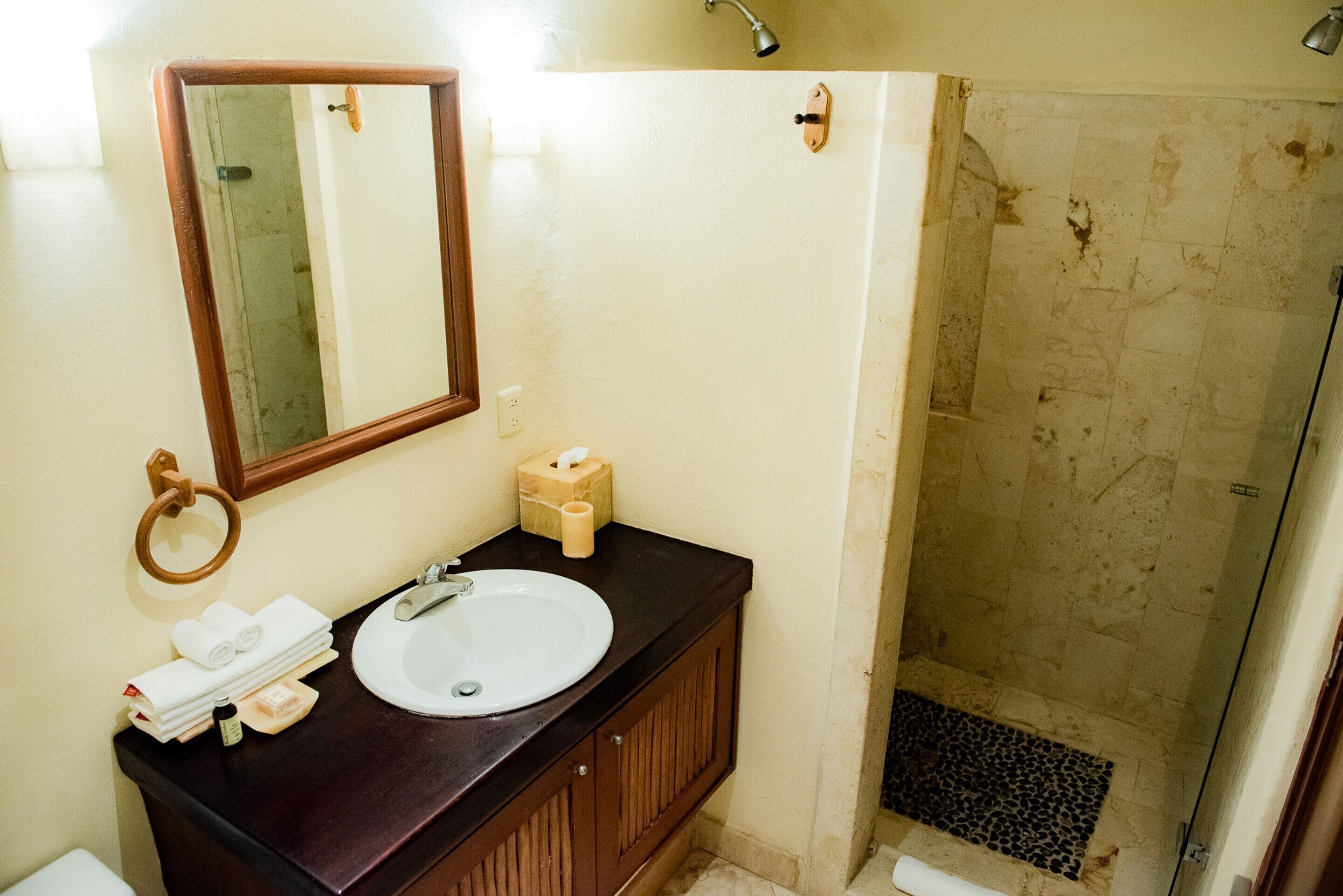A bathroom with a sink, mirror, towel rack, and shower area.