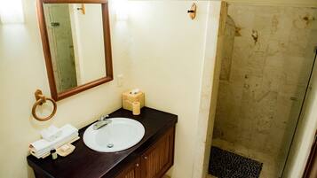 A bathroom with a sink, mirror, towel rack, and shower area.