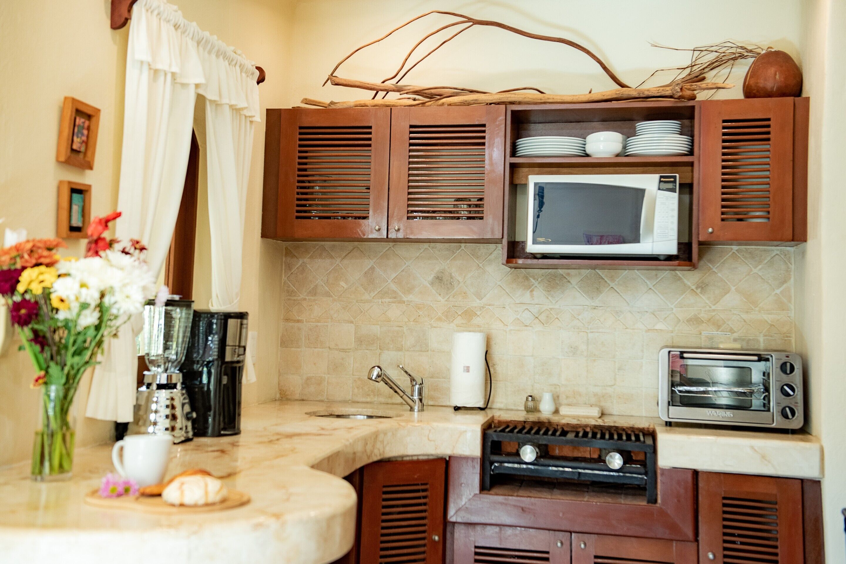 A kitchen with wooden cabinets, a microwave, a toaster oven, a coffee maker, and a sink.
