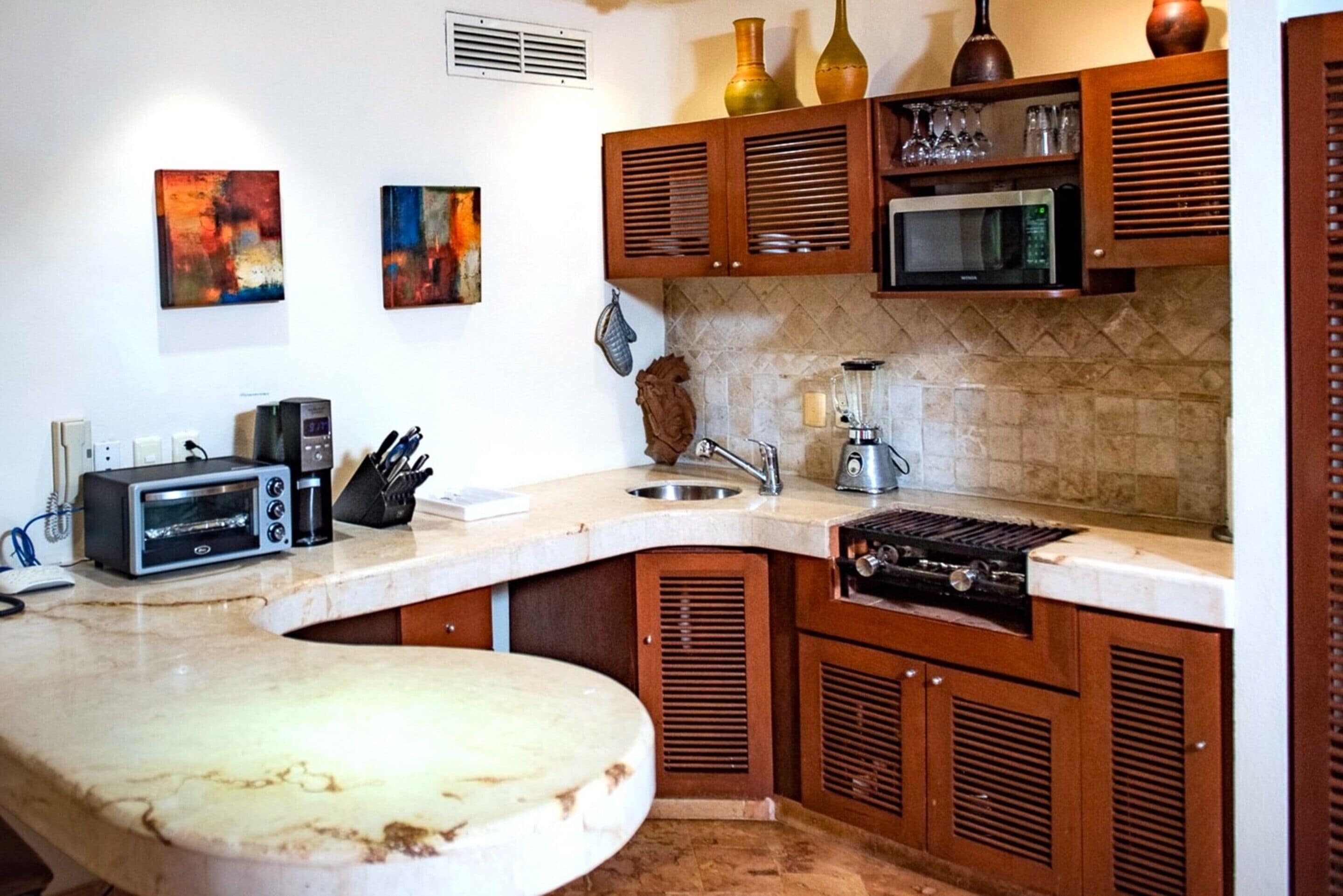 A kitchen with wooden cabinets, a microwave, a toaster, and a sink.