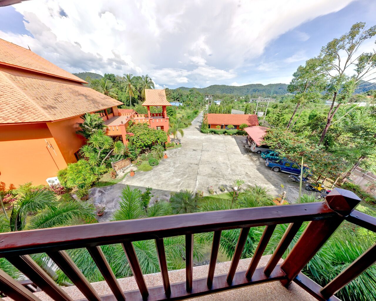 A courtyard with a paved area, surrounded by greenery and buildings with red roofs.