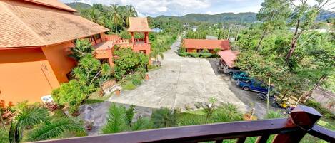 A courtyard with a paved area, surrounded by greenery and buildings with red roofs.
