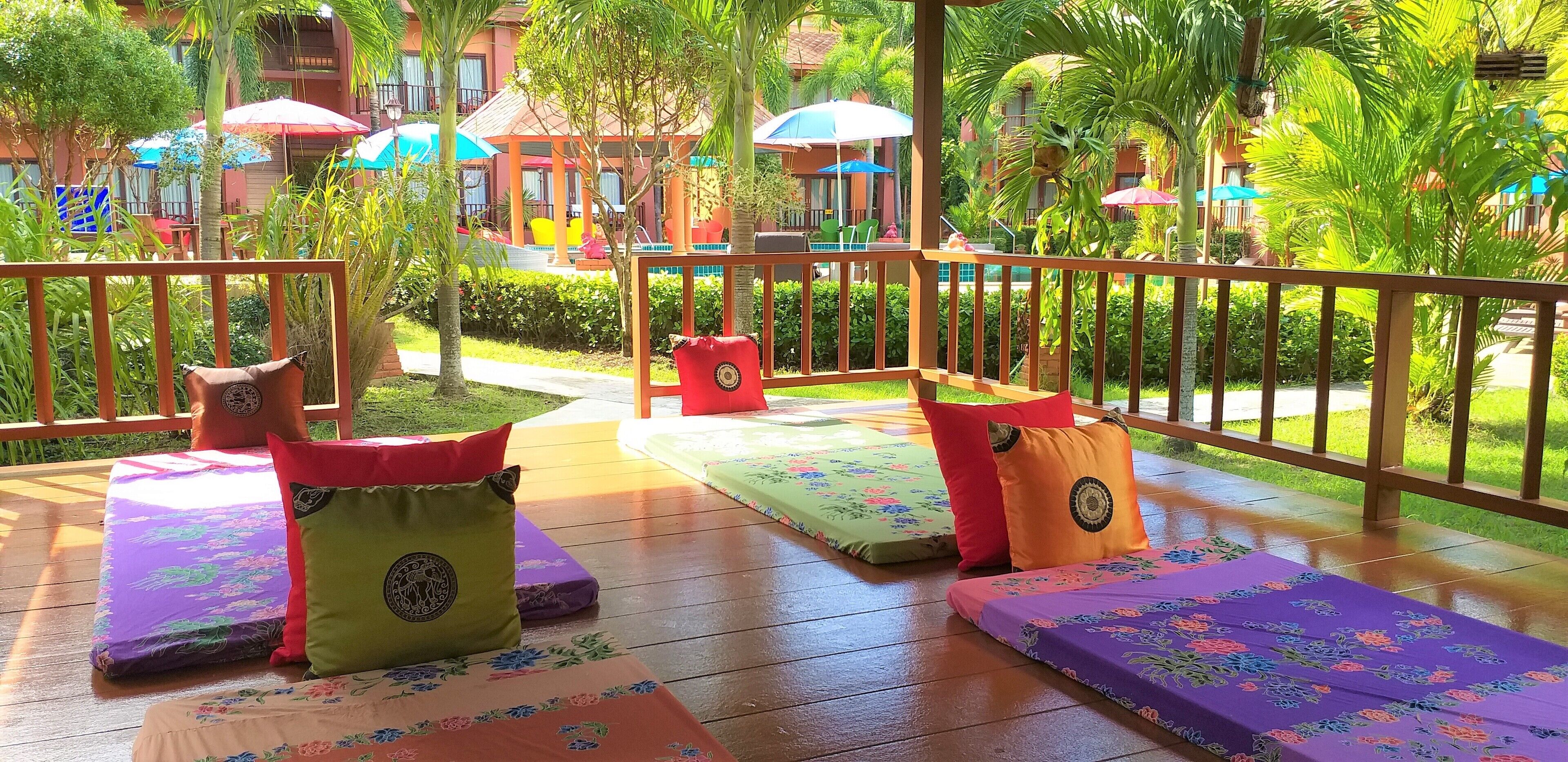 A deck with cushioned seating and a pool in the background.