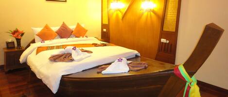 Una habitación de hotel con una cama en forma de barco de madera, dos mesitas de noche, una mesita de noche con un florero y un cuadro en la pared.