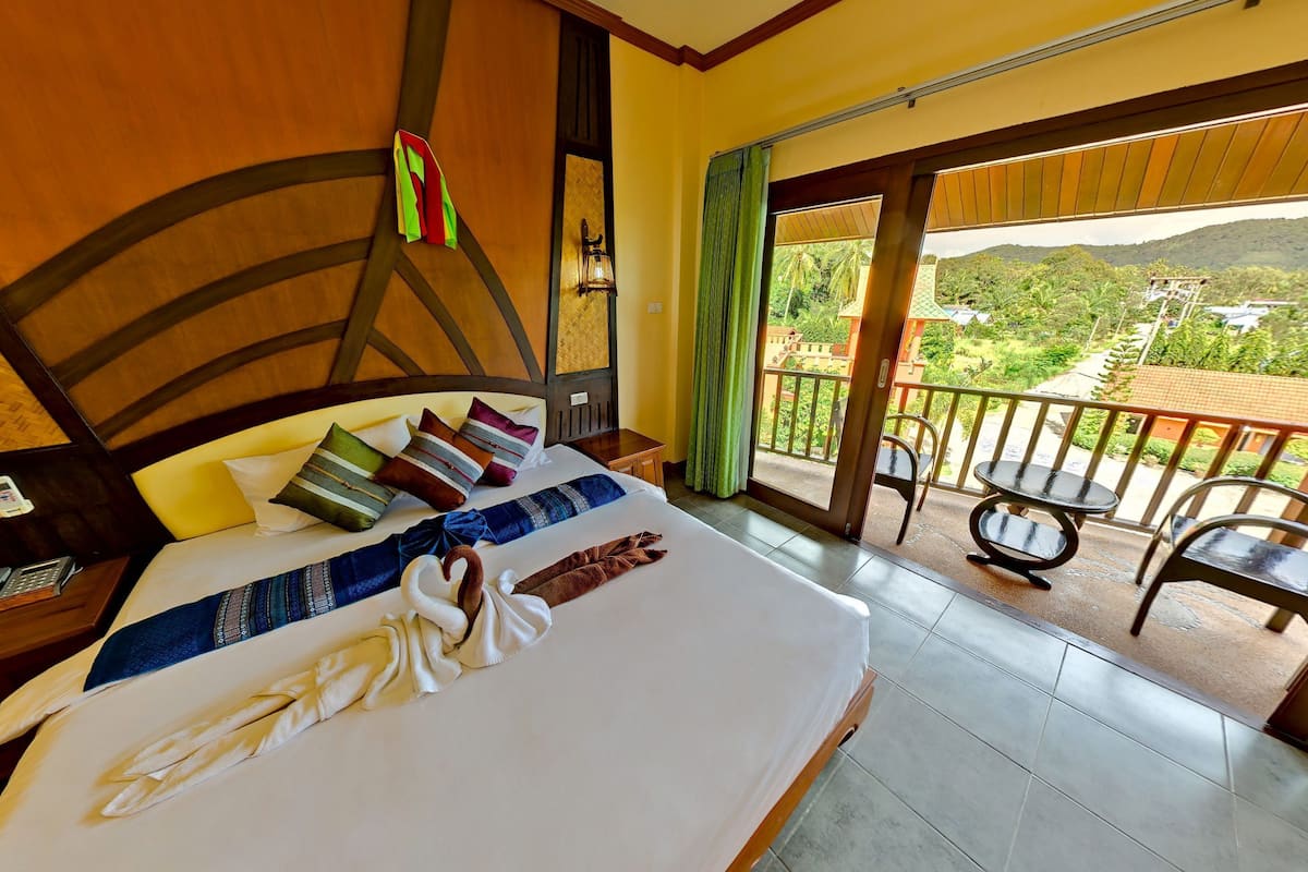 Habitación de hotel con cama, escritorio, teléfono y balcón con vistas al paisaje.