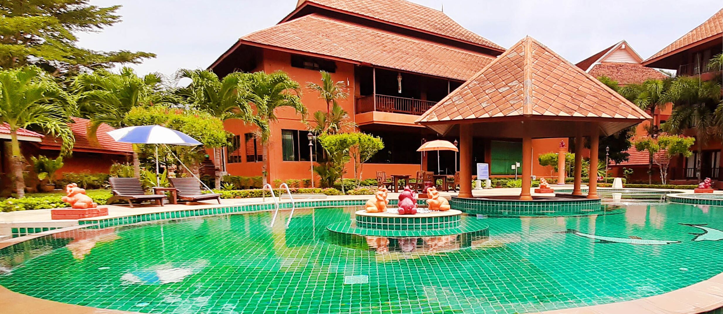 Un resort con piscina central, sillas de descanso y una zona de estar techada.