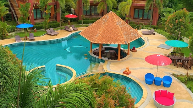 Un resort con piscina, sillones de descanso y un pabellón.