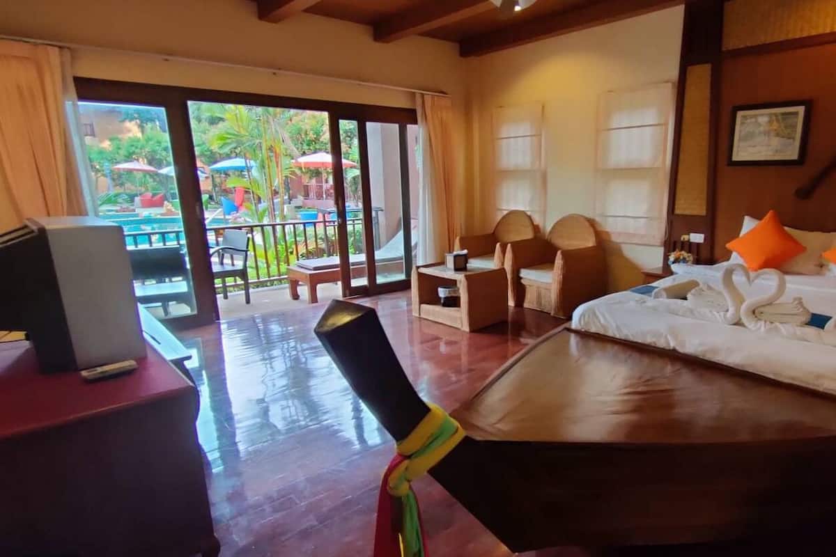 Habitación de hotel con cama, escritorio con computadora, una silla y vistas al área exterior con sombrillas.