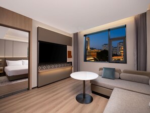 A modern hotel room with a bed, a TV, a sofa, and a view of the cityscape at dusk. - Holiday Inn Guilin Qixing by IHG (Guilin)