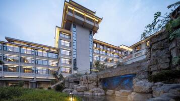 Ein modernes Hotel mit mehreren Etagen, einer Steinbrücke und einem Wasserspiel.