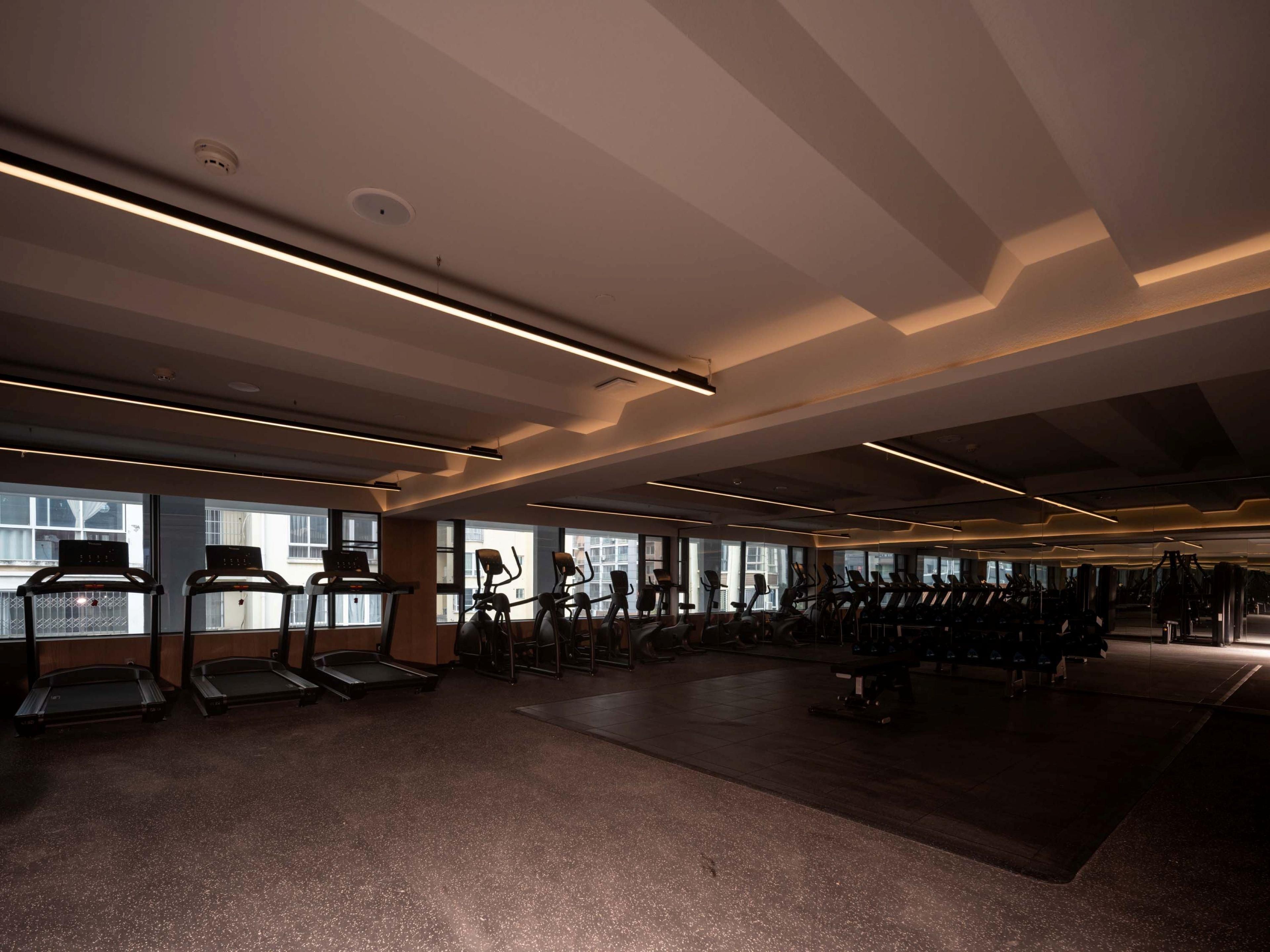 Un gimnasio con cintas de correr, bicicletas estáticas y máquinas de pesas.