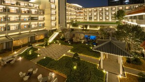 Un hotel con varios pisos, un patio central con asientos y un edificio de estilo tradicional que cuenta con una torre.