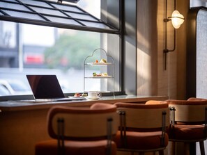 Un comedor con una computadora portátil, un soporte escalonado para postres y sillas acolchadas.