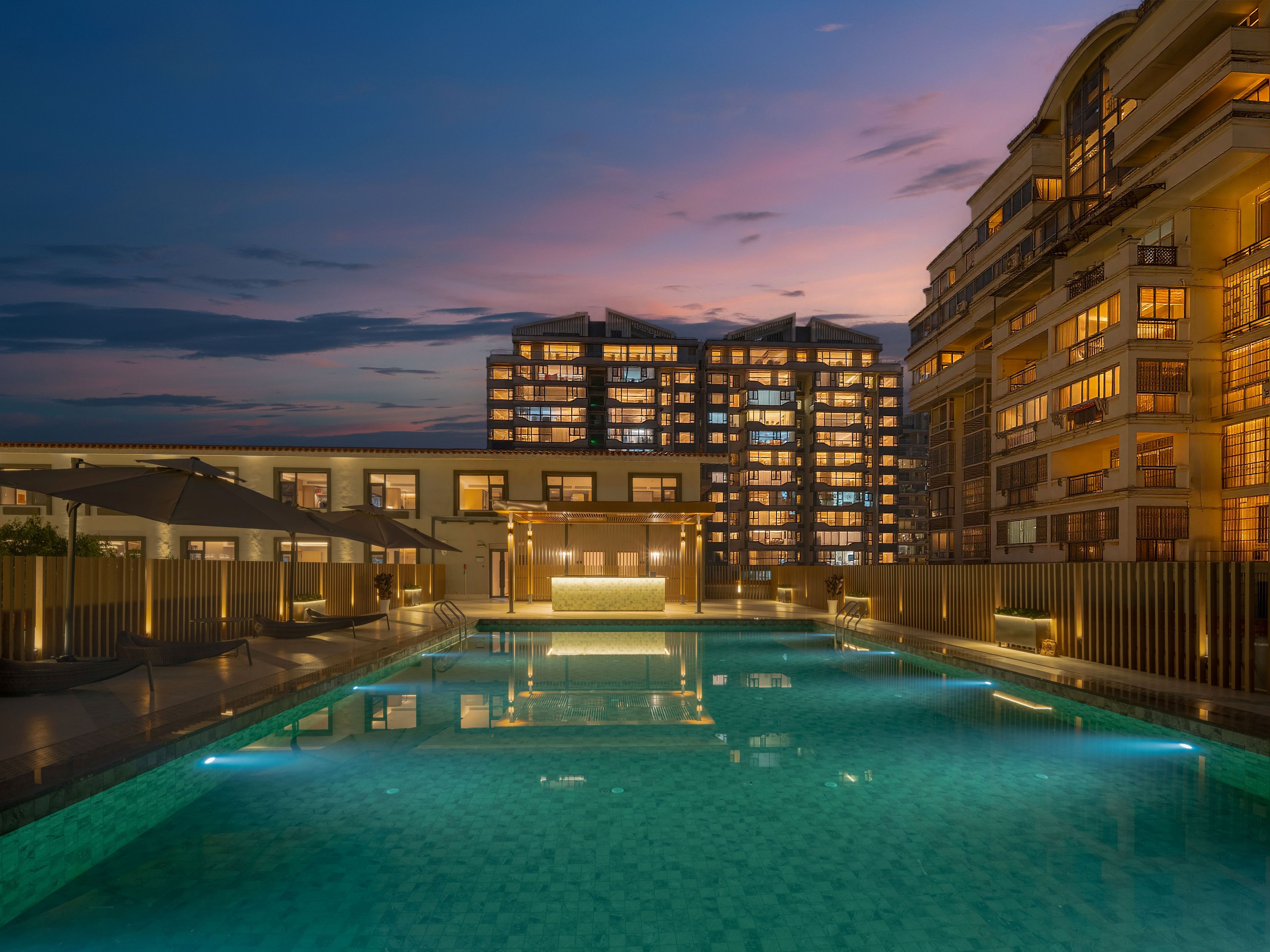 Un hotel con piscina, varios balcones y una entrada bien iluminada.